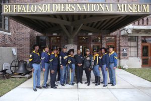 A photo of african american men dressed like buffalo soldiers outside of the buffalo soldier museum