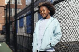 A girl standing in front of a fence while parents teach your teen to manage their time well