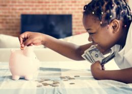 African american girl putting money into a piggy bank for financial lessons