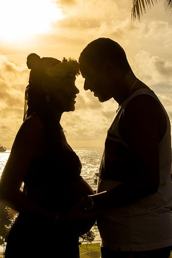 Silhouette of a pregnant couple pressing foreheads together in a loving embrace.