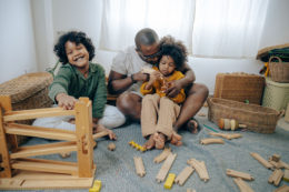 African american father puts together a train set for an article on hot to teach responsibility to your kids.
