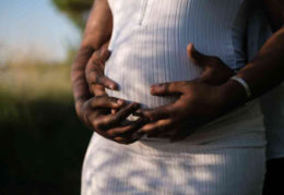 Boost your chances of pregnancy. African american man holding wife's pregnant belly.