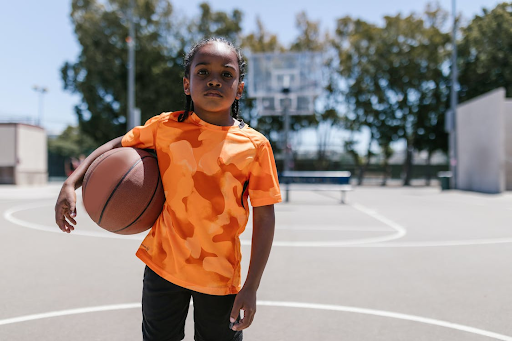 Alt description: a determined african american boy on the basketball court, embodying the joy of family sports activities.