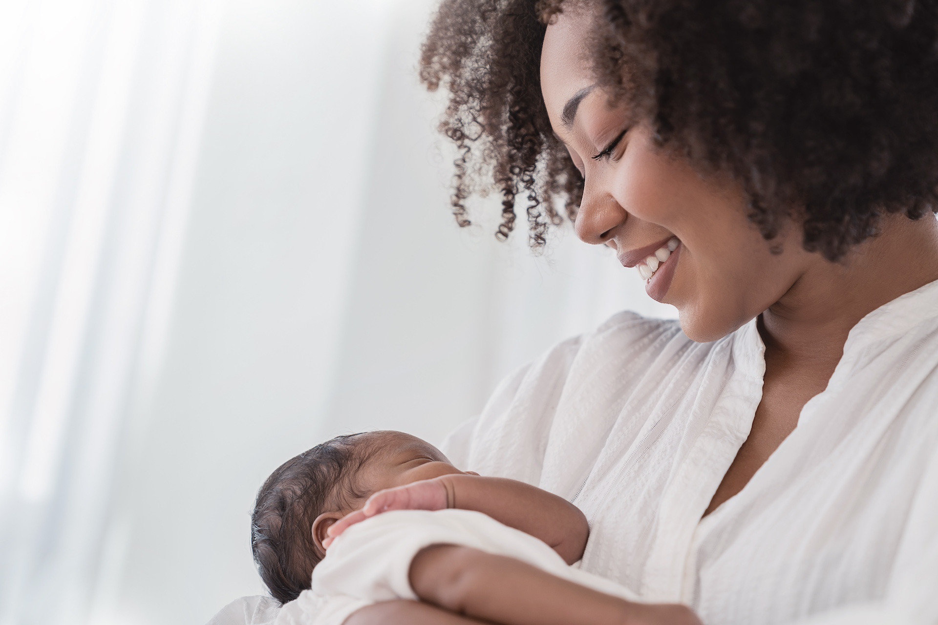 Close up portrait of beautiful young african american mother holding sleep newborn baby in hospital. Healthcare medical love black afro woman lifestyle mother's day.