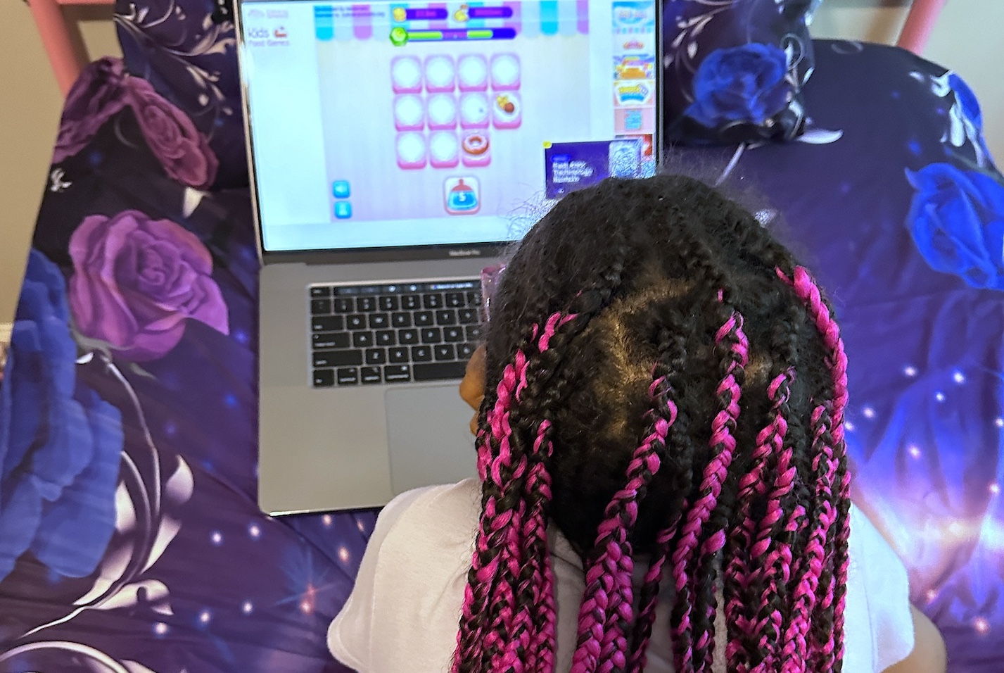 African american girl plays online kids' cooking games on a laptop