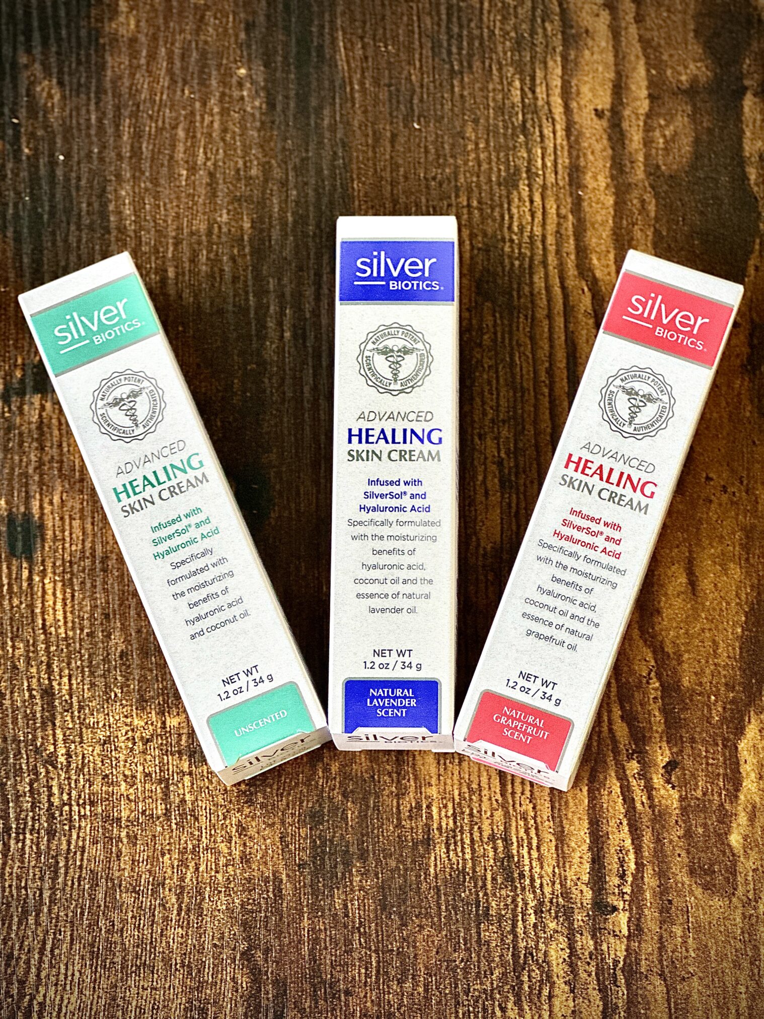 On a rustic wooden table, three tubes of silver biotics advanced healing skin cream are displayed, offering luxurious self-care gifts in natural lavender, grapefruit, and unscented options for soothing dry, cracked skin.