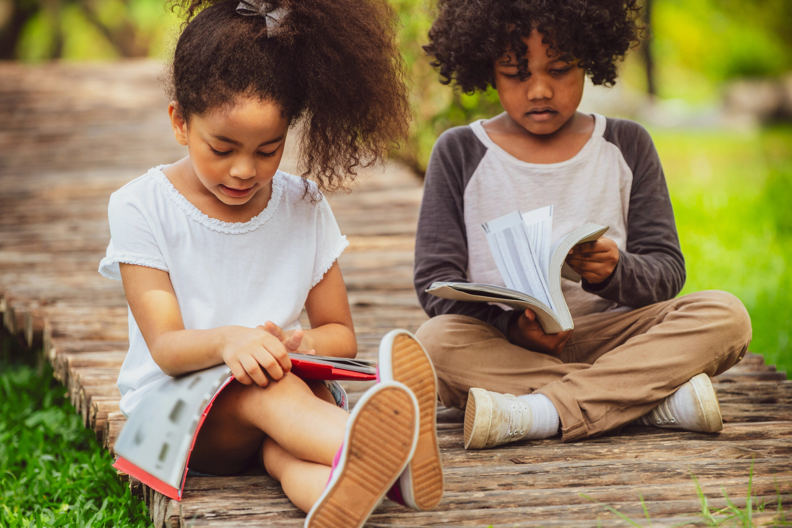 Two african american children reading during the summer to prevent summer slide