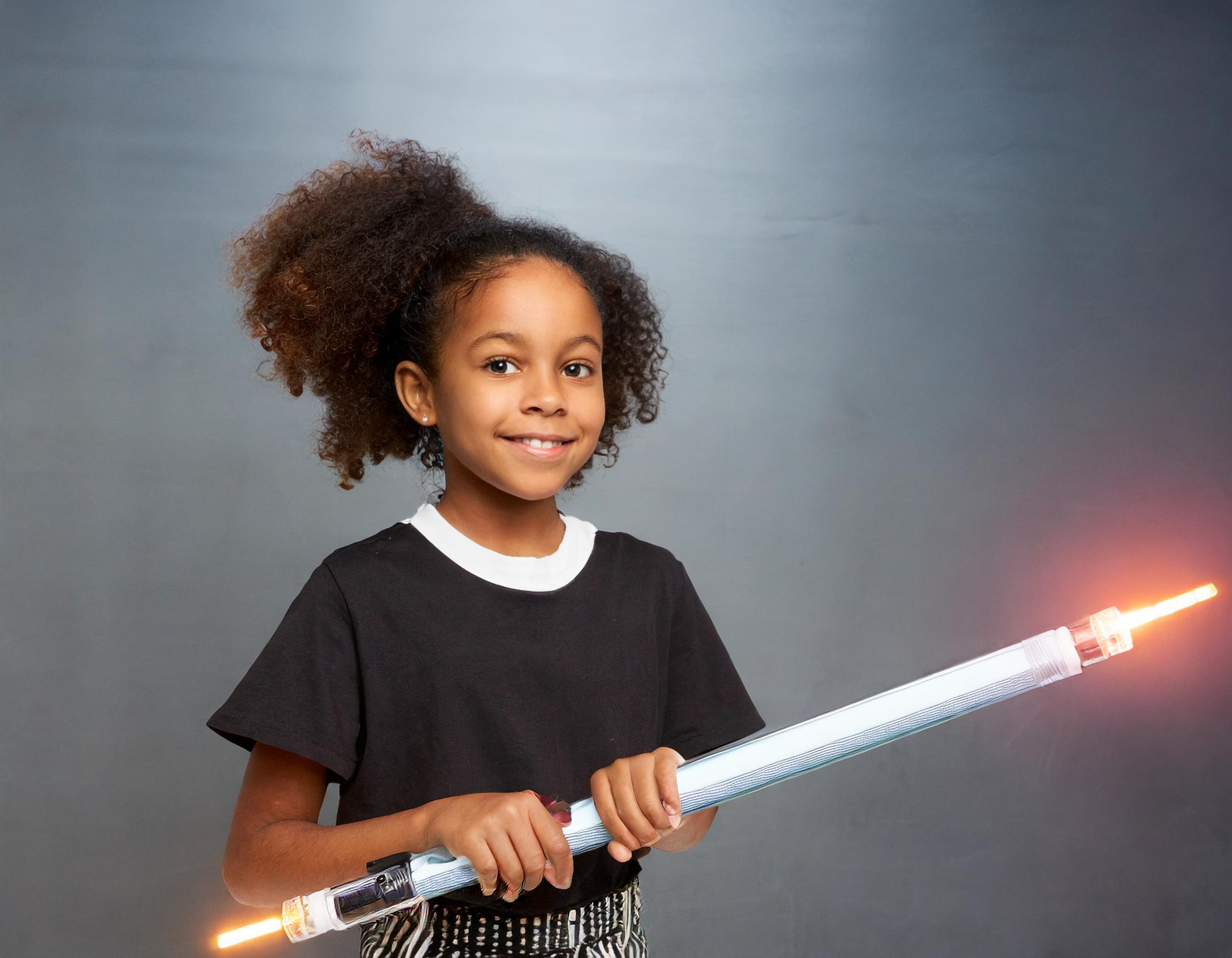 An african american girl hold a lightsaber for an article on kids who love star wars