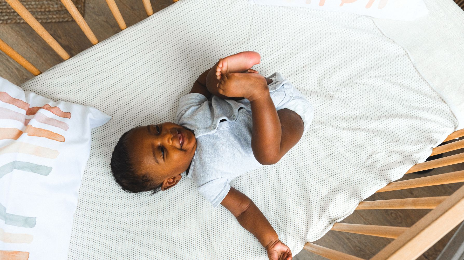 An african american baby is in the bed being watched on a baby monitor.