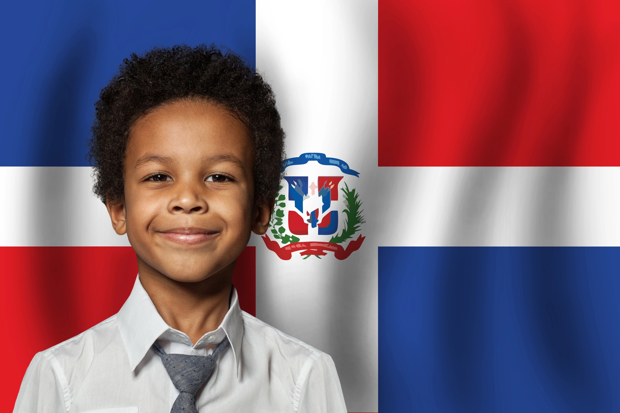 Smiling african american boy standing in front of a dominican flag, symbolizing bilingualism and language learning opportunities for black children through immersive education programs