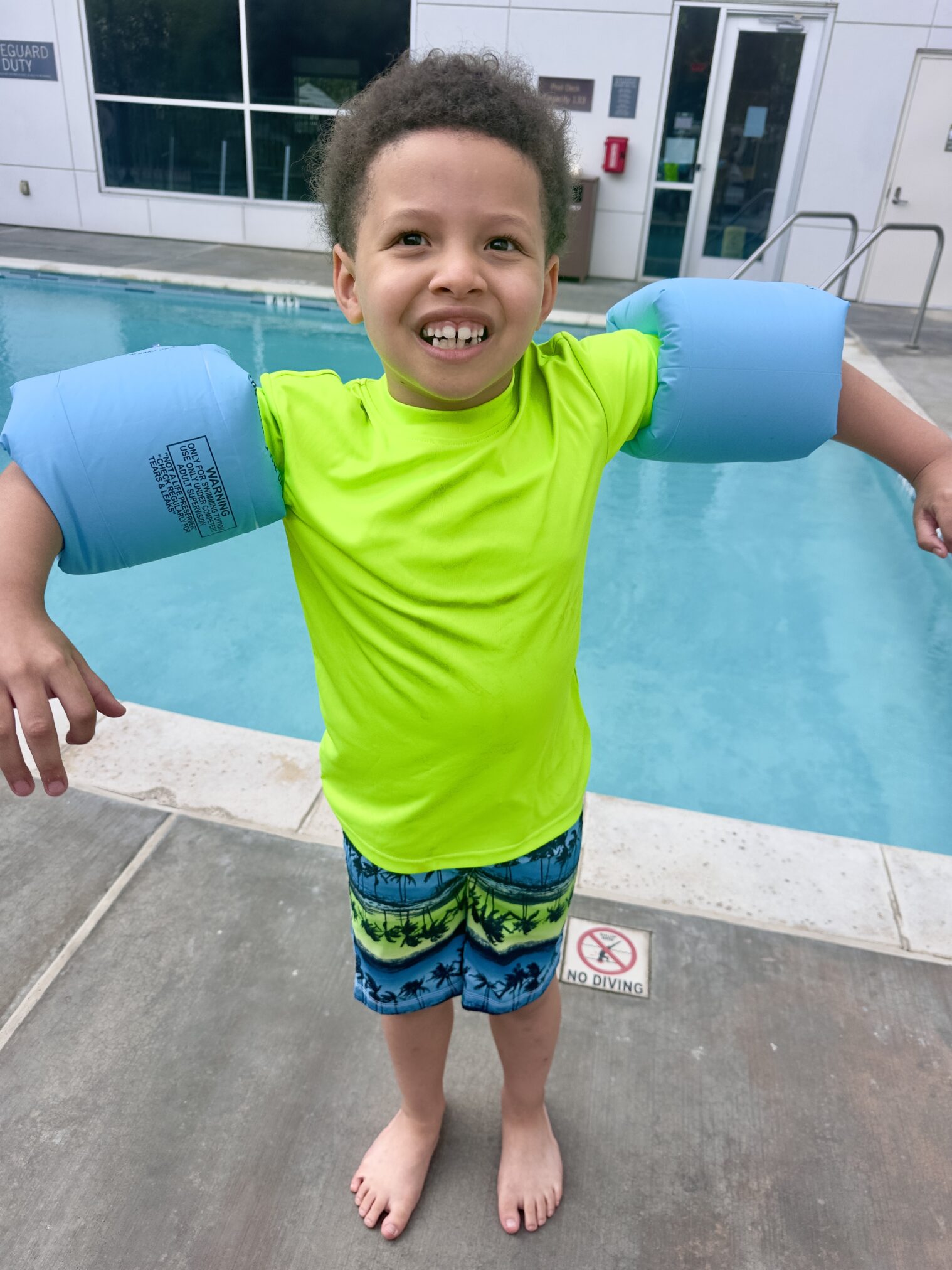 A young black boy with floaties on his arms at the swimming pool at the hyatt house in irvine, california.