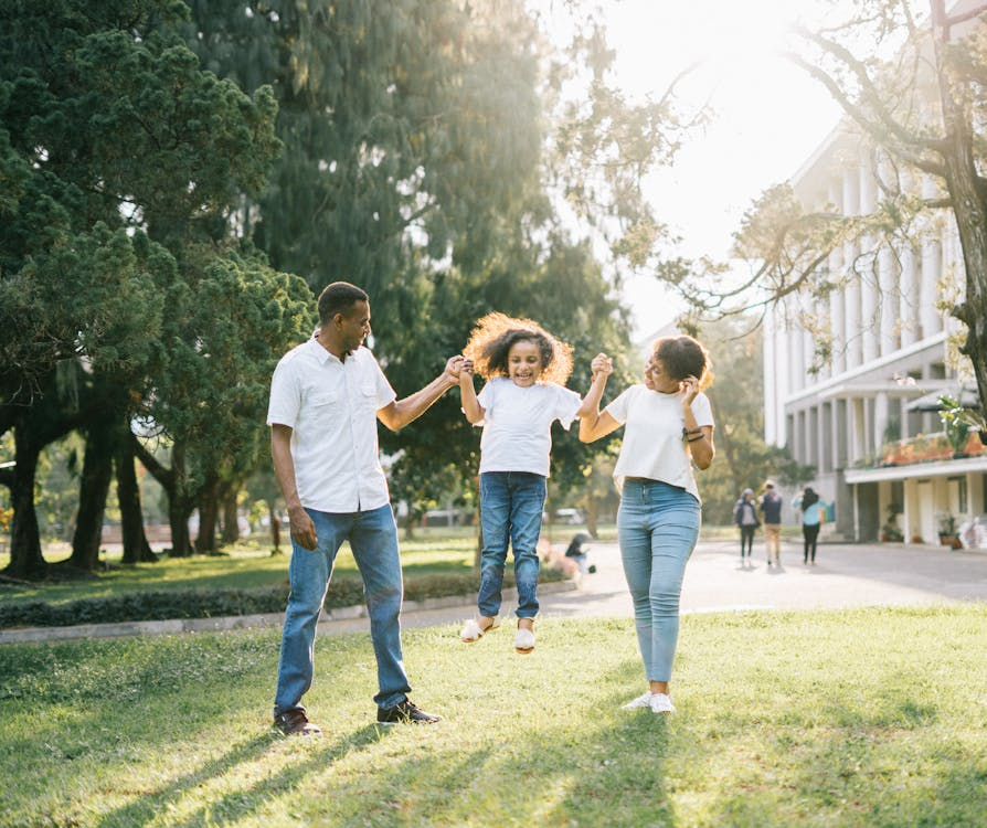 What does 'best interests of the child' mean in family court decisions? Black parents swinging their child joyfully in a sunny park, representing family unity and the importance of child well-being in family court custody decisions.