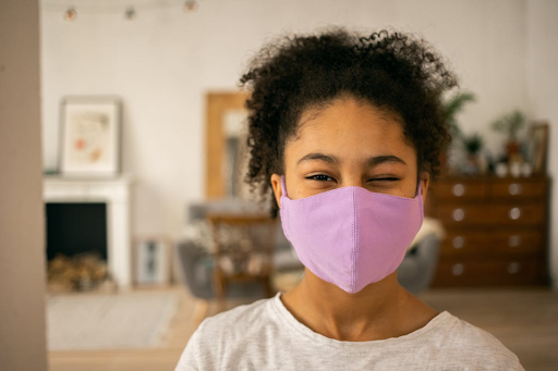 A smiling teen wearing a purple face mask stands indoors, symbolizing teens exploring rewarding careers in healthcare.