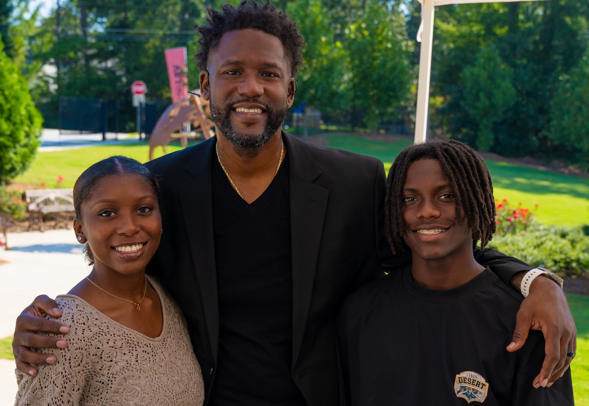 Dr. Terence lester holds his two children, zion and tj, smiling together during a warm family photo. The wide horizontal photo captures black joy, love, and connection.