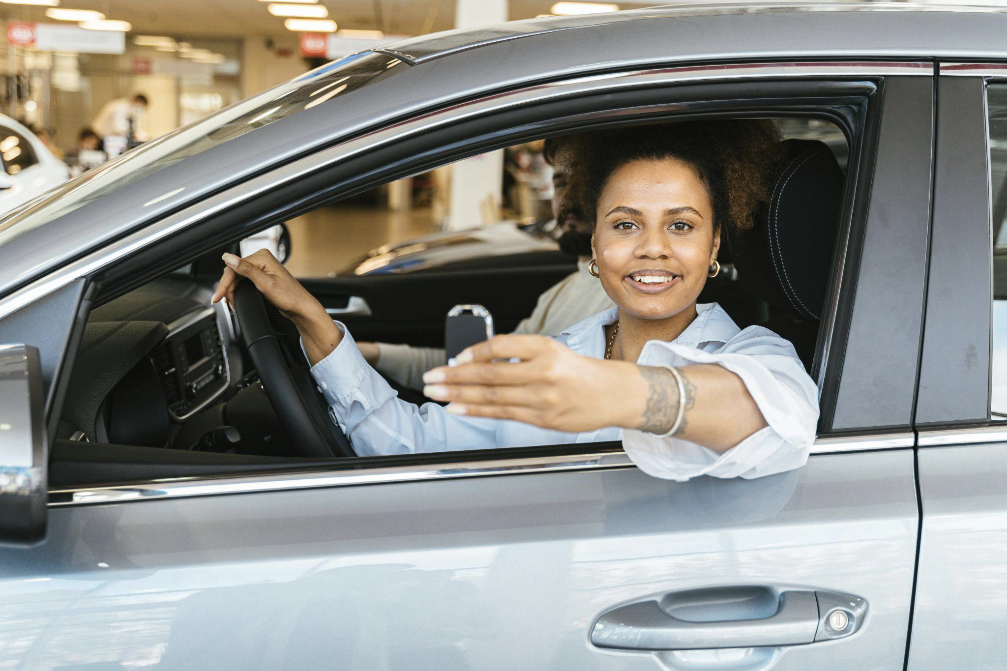 African american woman buying a salvage title vehicle at a dealership while sitting inside a silver suv