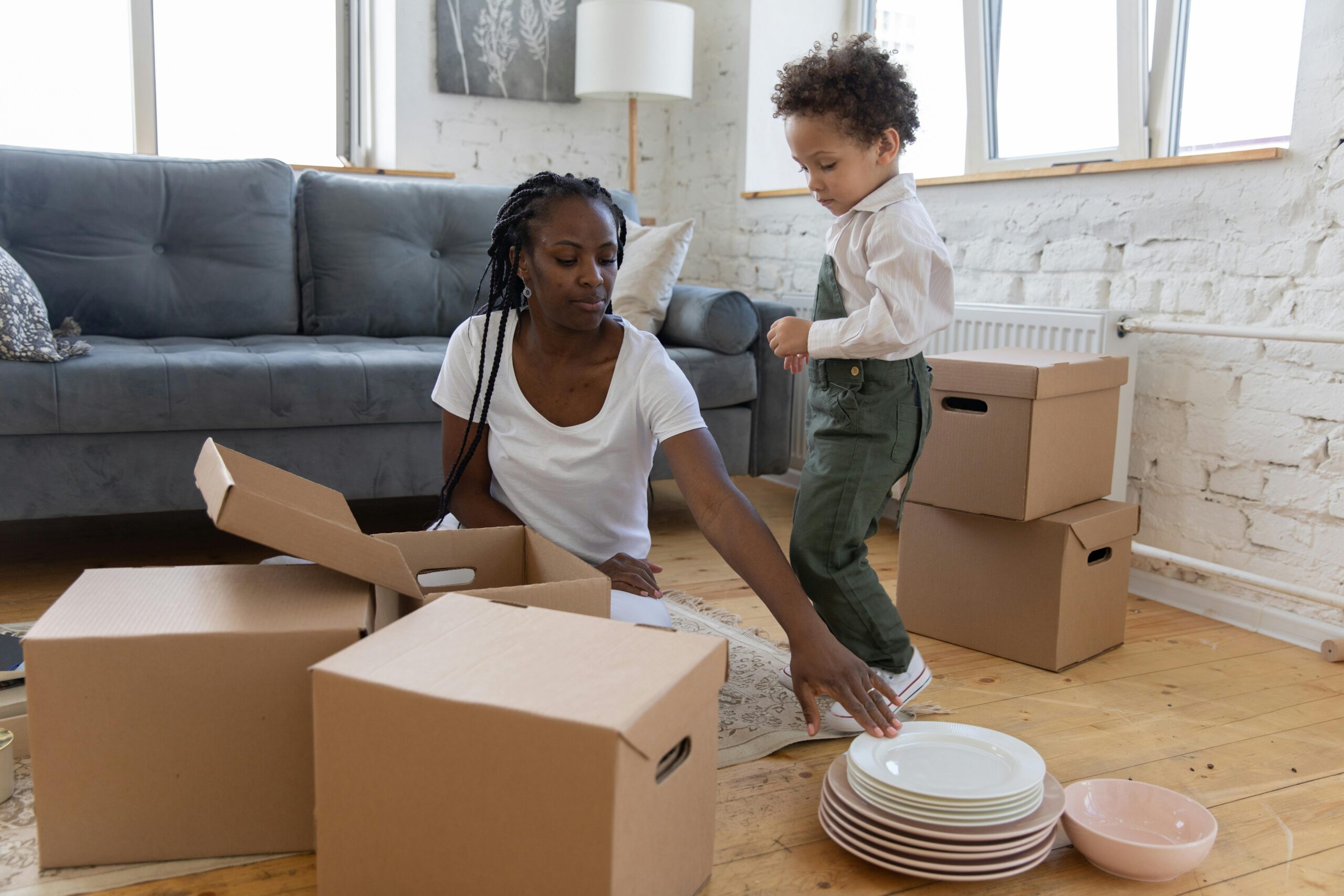 African american mother and child unpacking moving boxes together to help kids adjust to a new home faster after relocation.