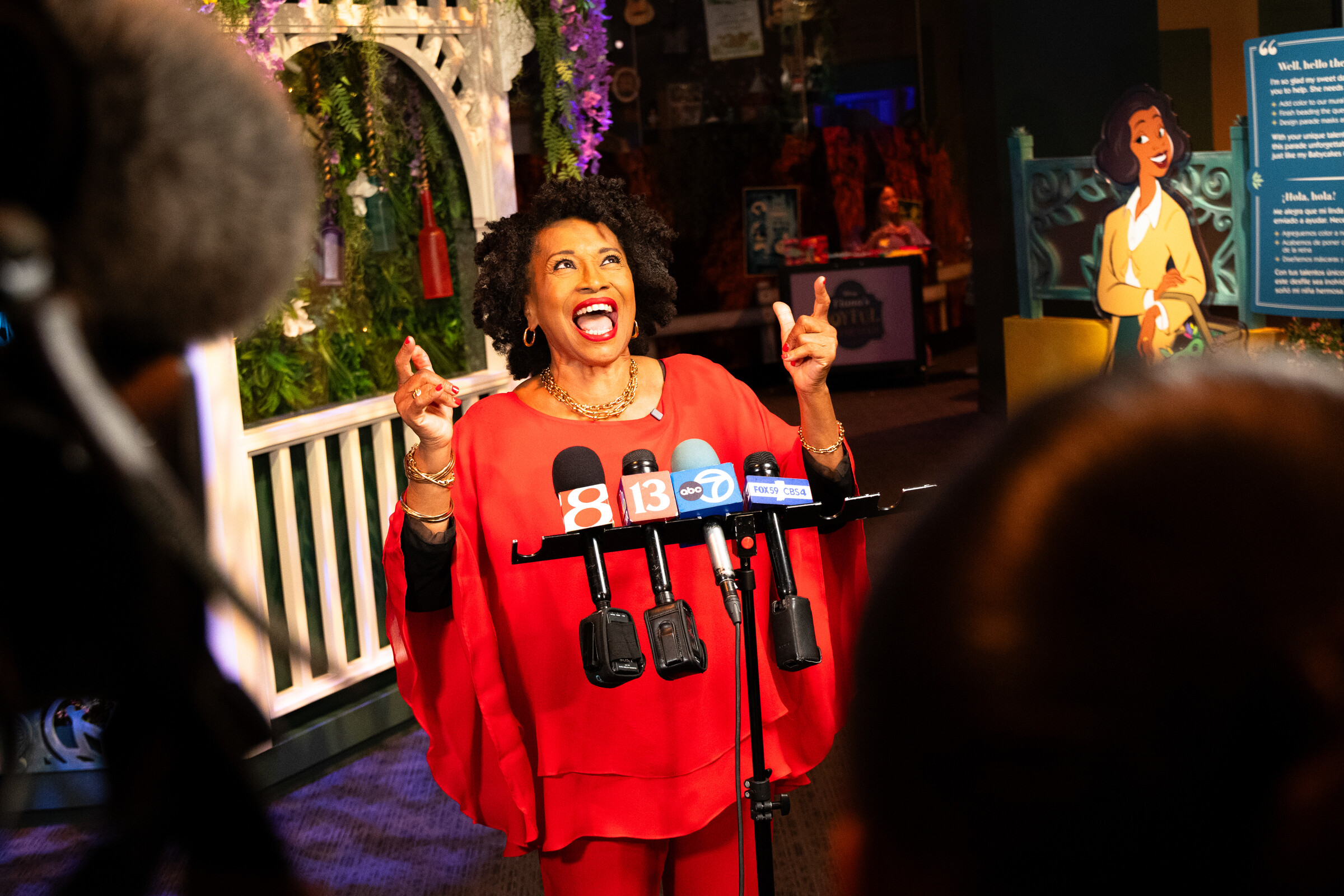 Jenifer lewis laughs joyfully while speaking to local news cameras at the exhibit.
