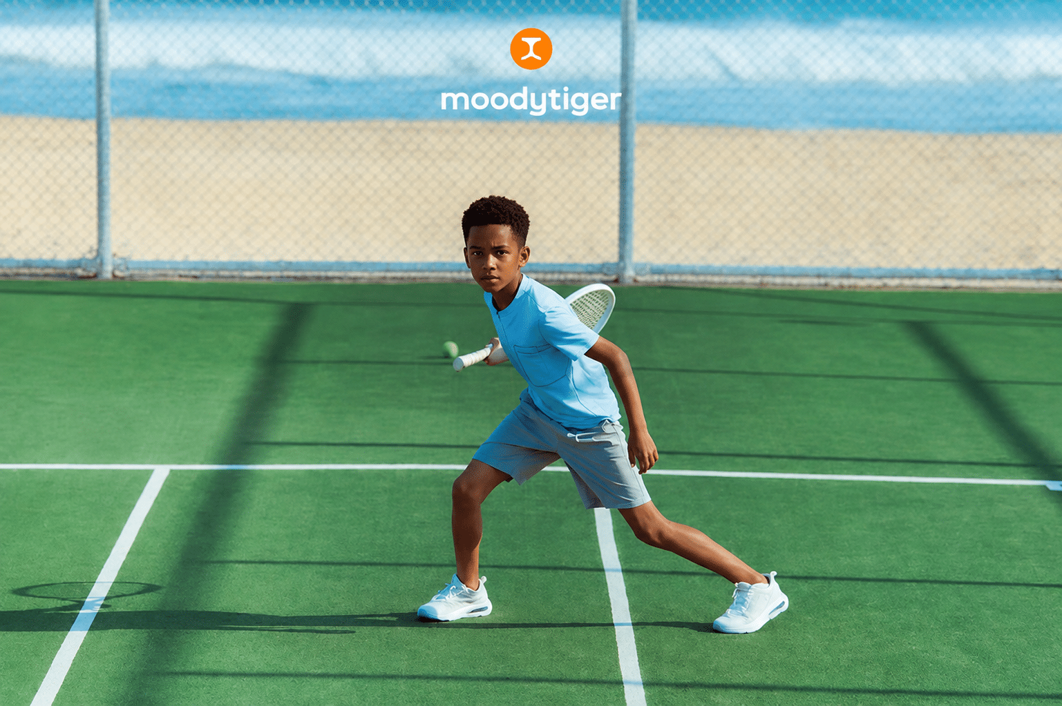African american boy wearing kids activewear during school-age outdoor tennis practice