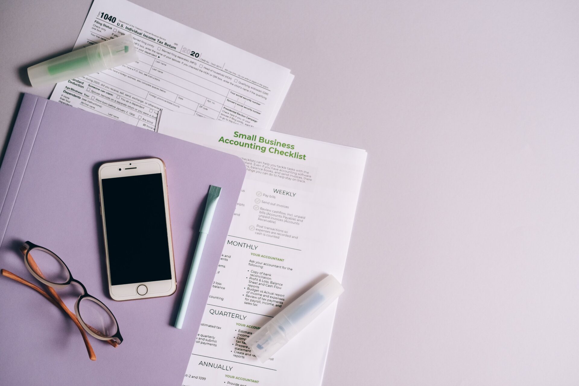 Financial planning essentials, glasses taxes, iphone, folder for business.