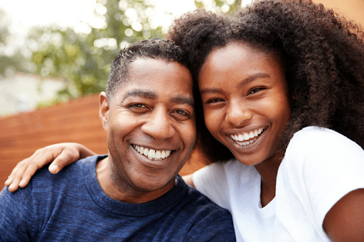 Black mother and teenage daughter talking warmly at home, supporting teen mental wellness, teen anxiety treatment, and black teen mental health.